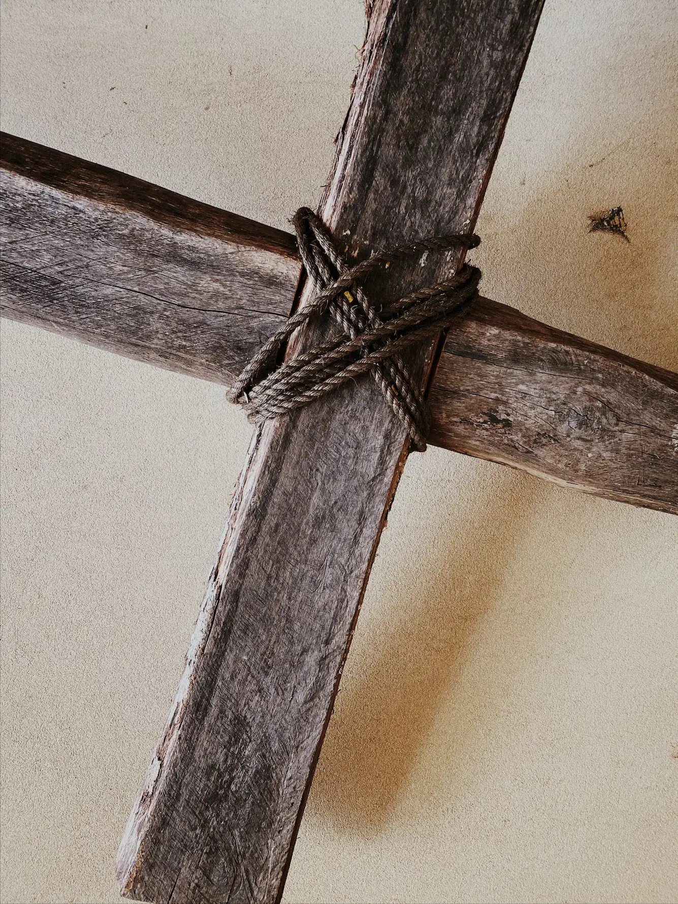 Image of a cross with brown rope tying it together. Rustic.